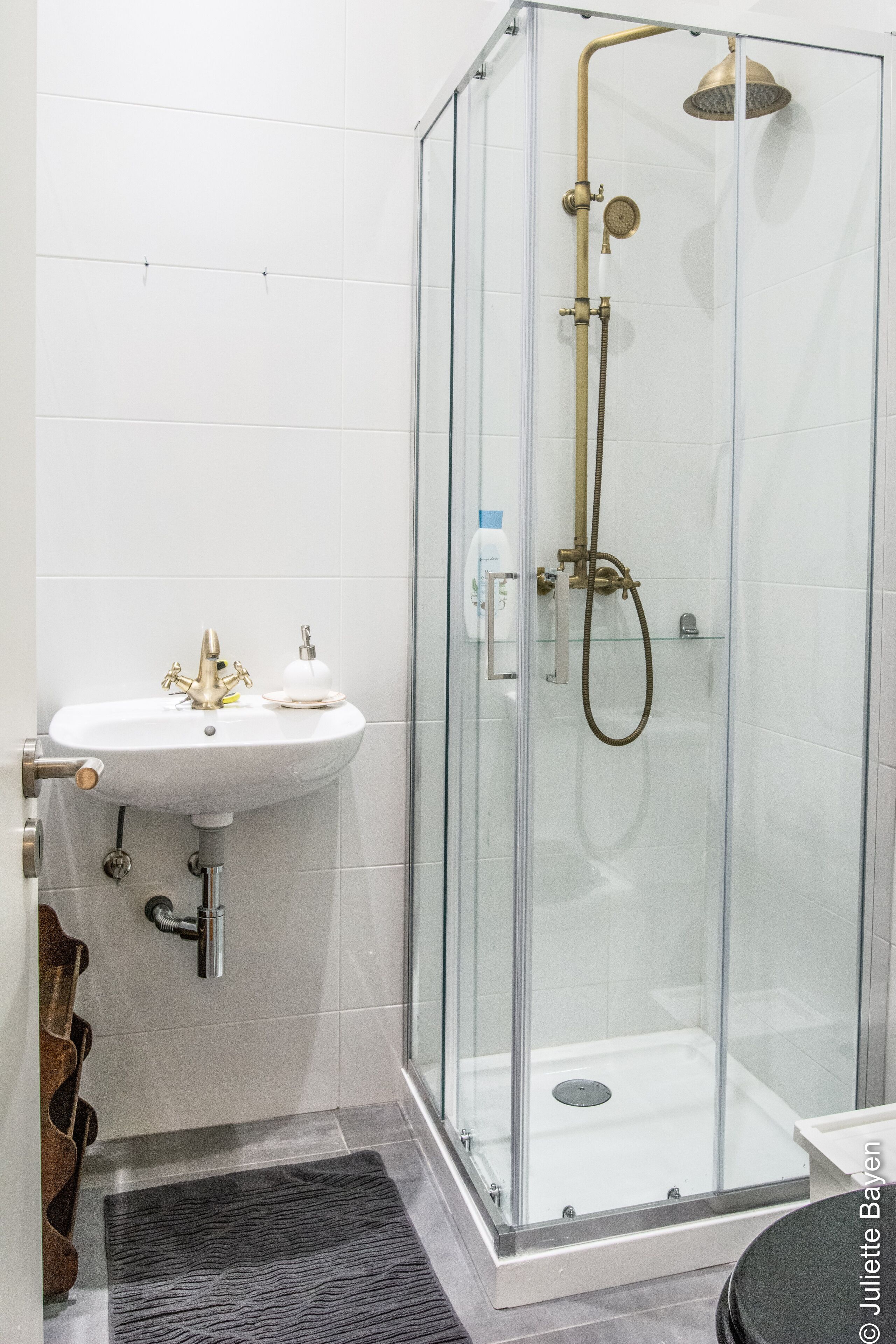 Ein modernes Badezimmer mit einer Duschkabine, einem Standwaschbecken und einer kleinen Ablagefläche.
