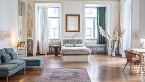 A spacious bedroom with a large bed, a sofa, and a dining area. - Azulejos Cais Sodré B&B (Lisbon)