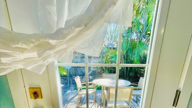Une pièce dotée d’une porte-fenêtre coulissante donnant sur un patio extérieur avec une table et des chaises.