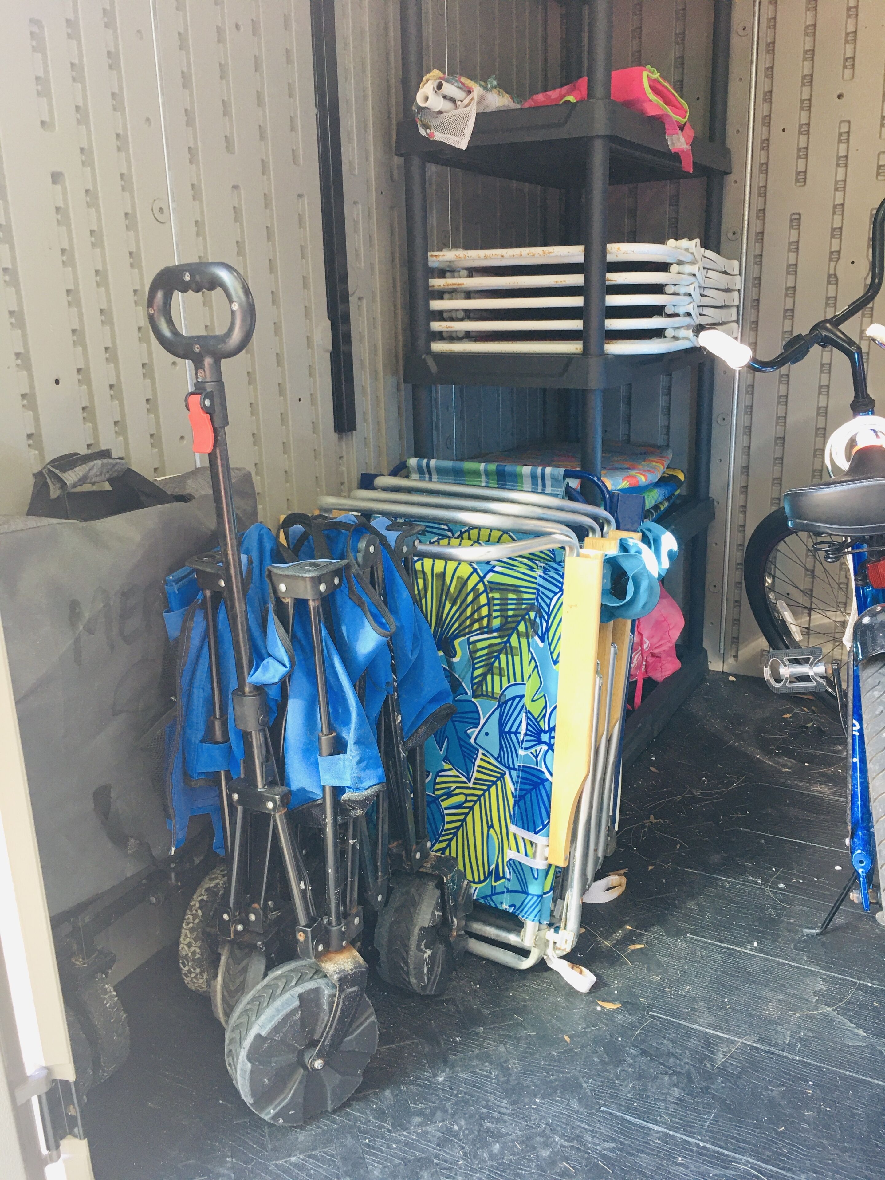 A storage area with a bicycle, a folding chair, and various bags and equipment.
