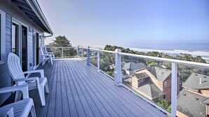 A wooden deck with white chairs and a glass railing overlooking a residential area and the ocean. - Ocean-View Lincoln City Retreat w/ 3 Viewing Decks (Lincoln City)