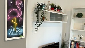 Una sala de estar con una televisión de pantalla plana, una estantería, una chimenea y una obra de arte con un flamenco de neón.