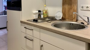 Una cocina moderna con horno empotrado, pileta de acero inoxidable y tabla de cortar de madera.