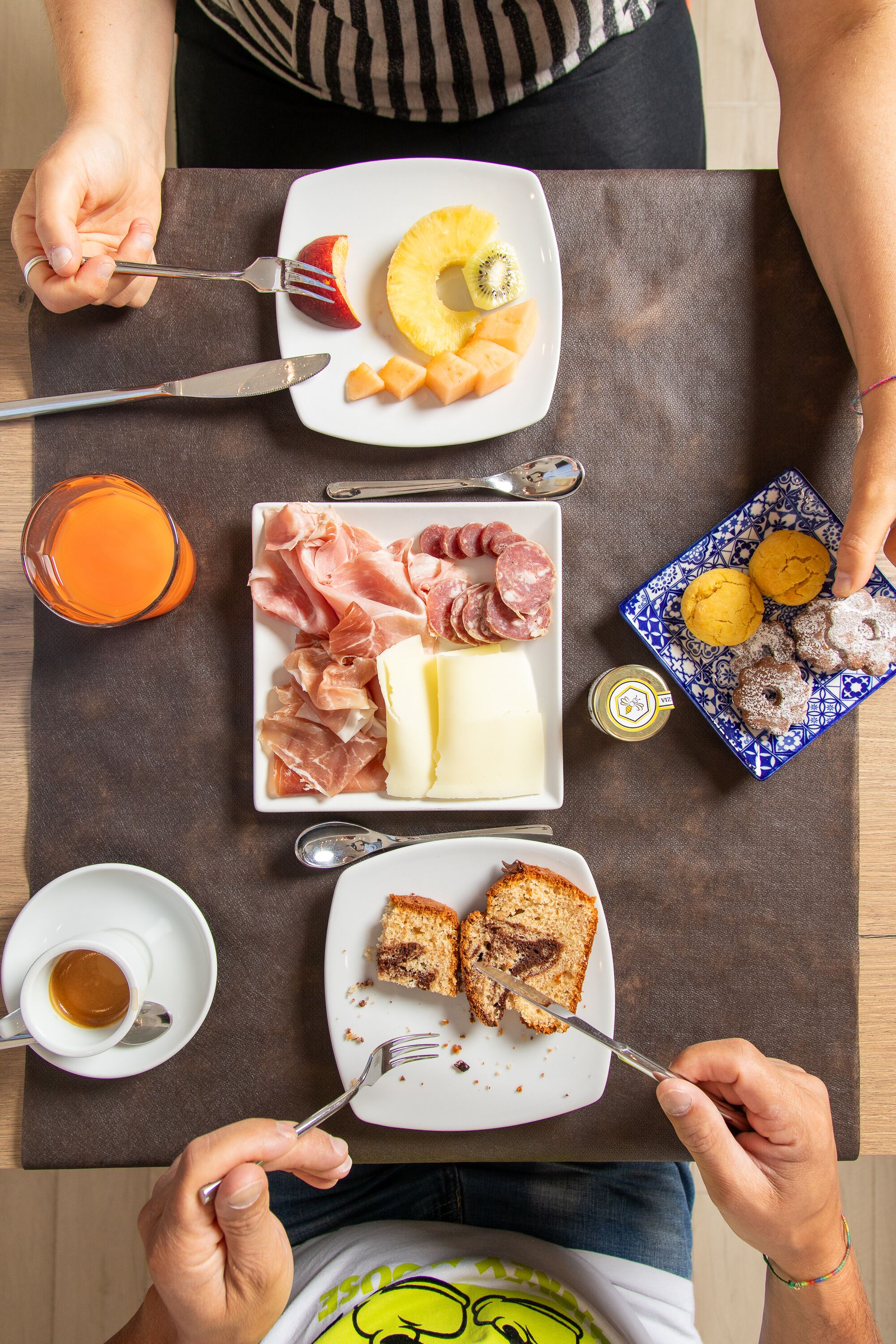 Un desayuno con platos de comida, un vaso de zumo de naranja y una taza de café.