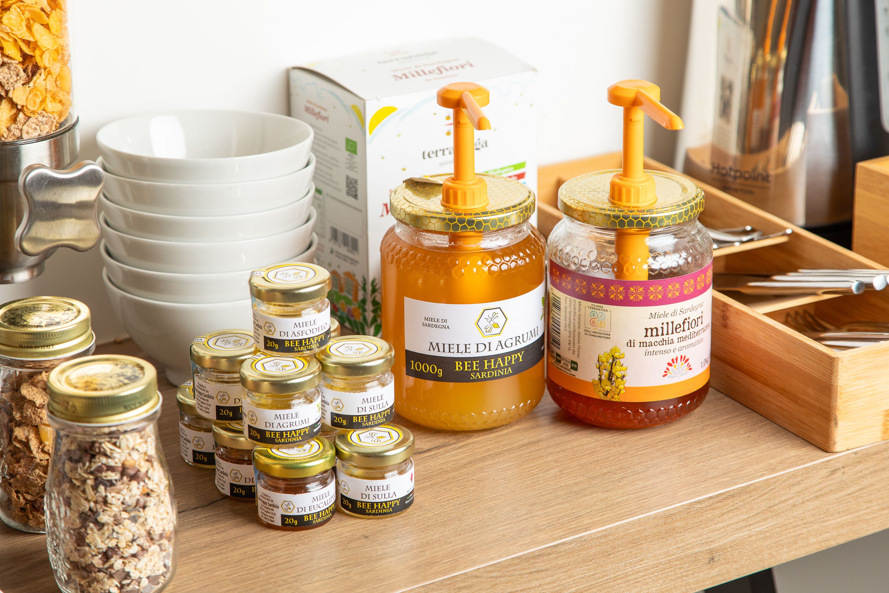 On peut voir une variété d’aliments, notamment des pots de miel et des pots de fruits confits, disposés sur une surface en bois.