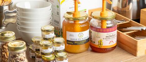 A variety of food items including jars of honey and jars of preserved fruits on a wooden surface.
