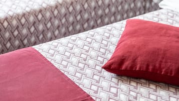 Ein Bett mit einem gemusterten Überwurf und zwei roten Kissen.