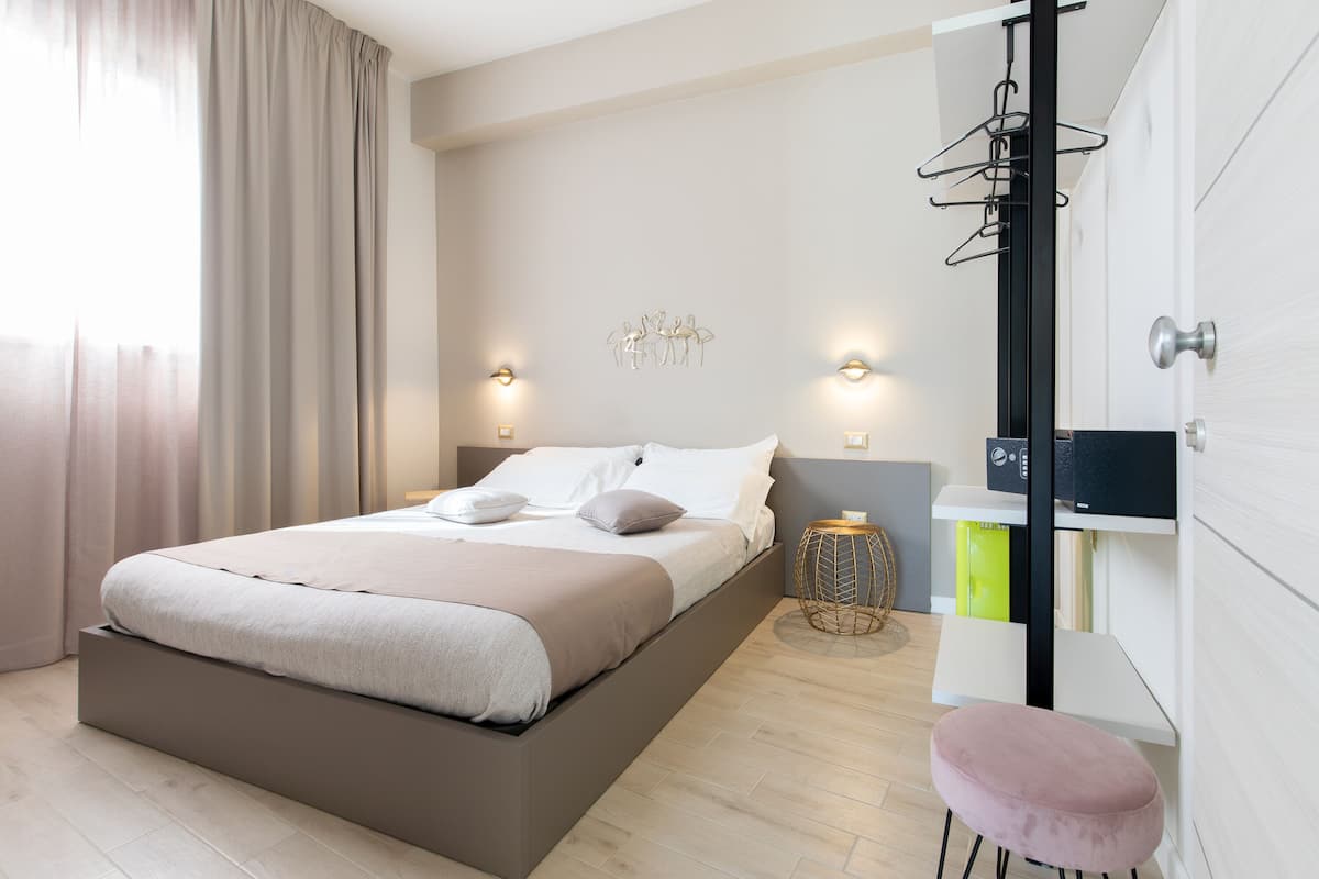 A modern bedroom with a bed, bedside tables, a wardrobe, and a small stool.