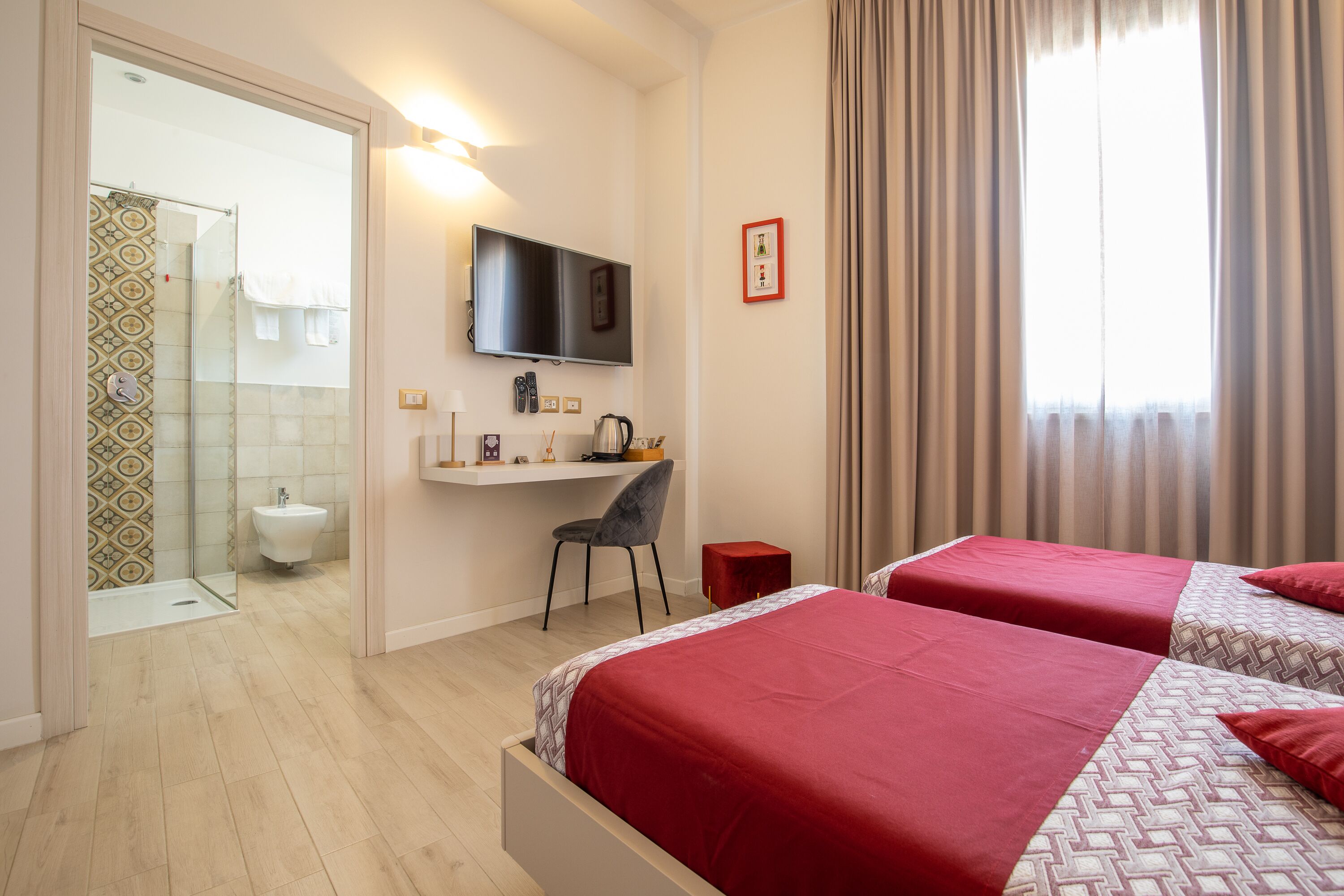 Une chambre d’hôtel avec deux lits, un bureau, une télévision et un espace douche.