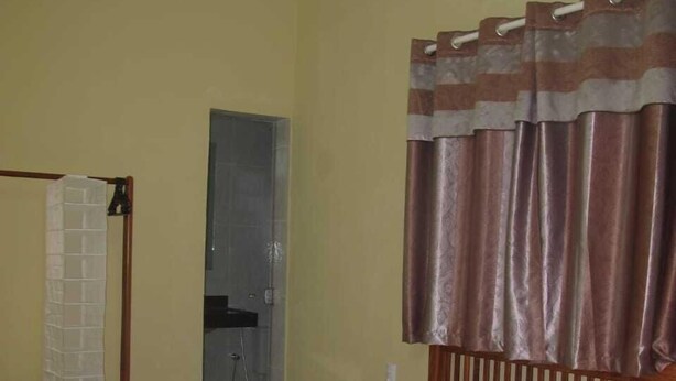 Quarto de hotel com cama, ar condicionado, chuveiro e porta-toalhas.