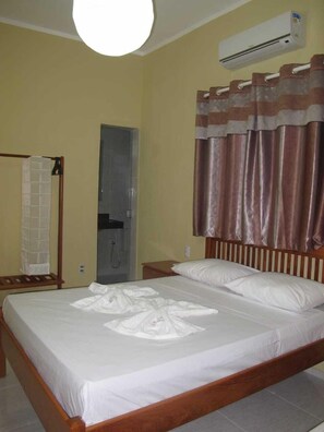 A hotel room with a bed, an air conditioning unit, a shower, and a towel rack. - Pousada Deisilia (Fortaleza)