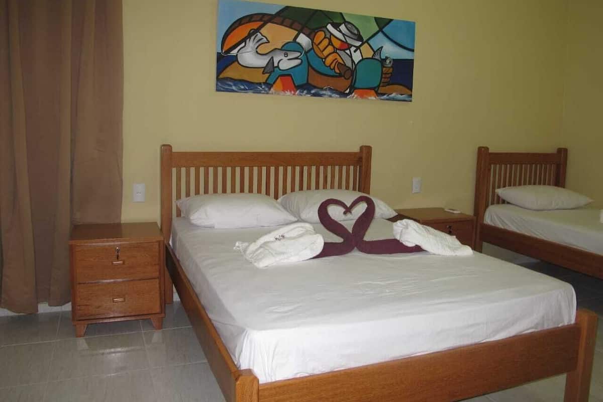 A hotel room with two wooden beds, a nightstand, and a painting on the wall.