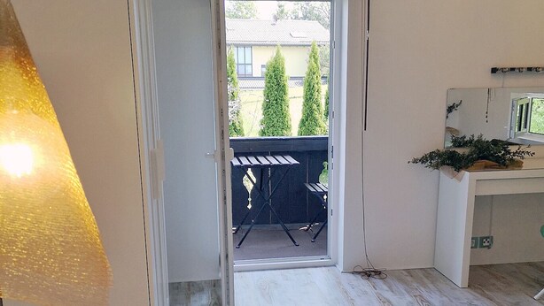 A room with a wooden floor, a door leading to an outdoor area with a view of trees and a fence, and a potted plant on the left. - Large vacation guest apartment Münsing near Lake Starnberg and the Alps 125m² ground floor + first floor (Münsing)