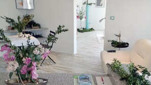 A modern living room with a marble floor, a white sofa, and a coffee table with a bowl of flowers. There is a bookshelf with books and a small plant. - Large vacation guest apartment Münsing near Lake Starnberg and the Alps 125m² ground floor + first floor (Münsing)
