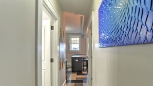 A hallway with a checkered floor, a kitchen area with a window, and a blue decorative wall. - Charming, condo #1 in Historic King James Building (Asheville)