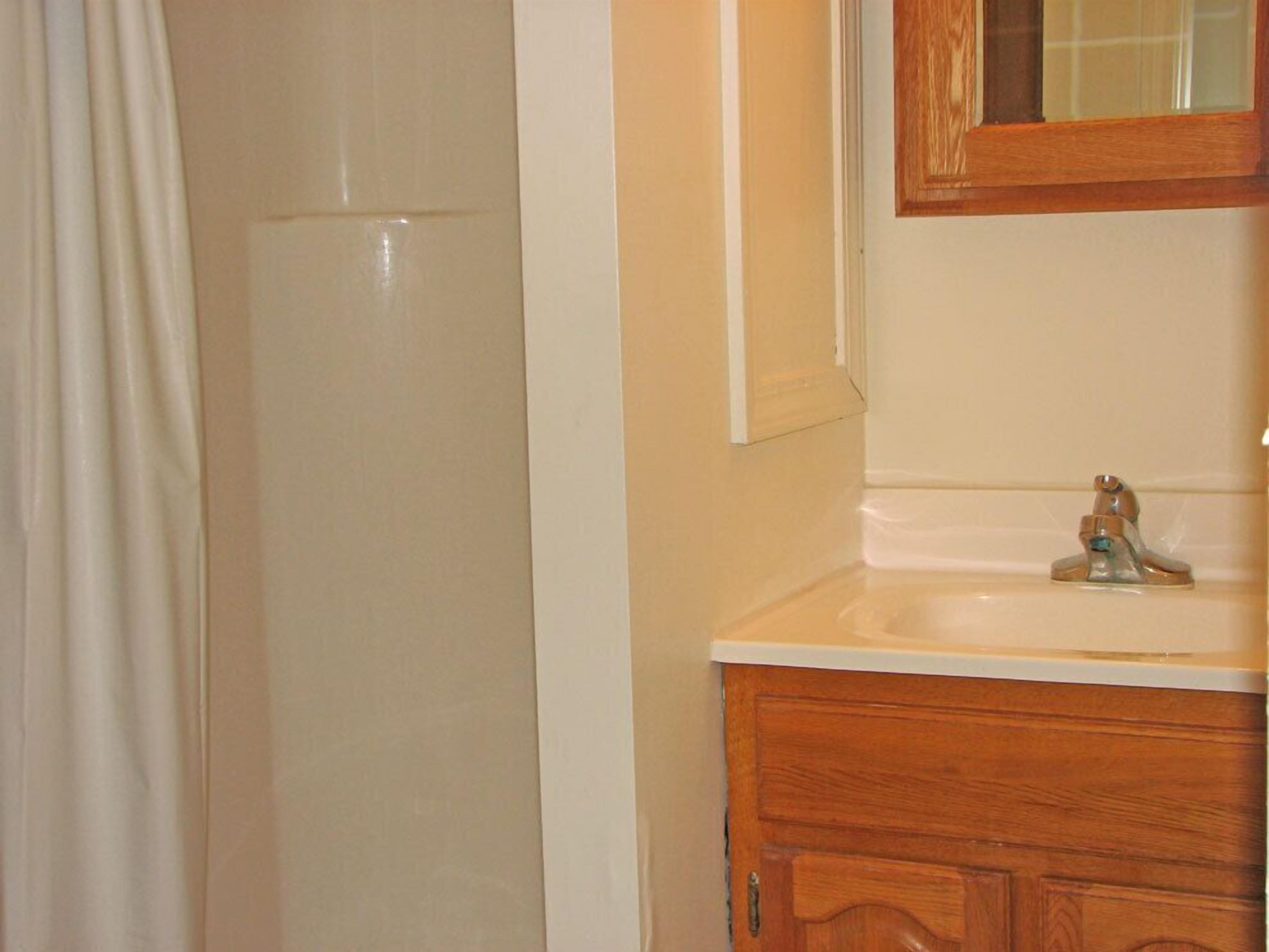 A bathroom with a wooden vanity, a mirror, and a shower curtain.