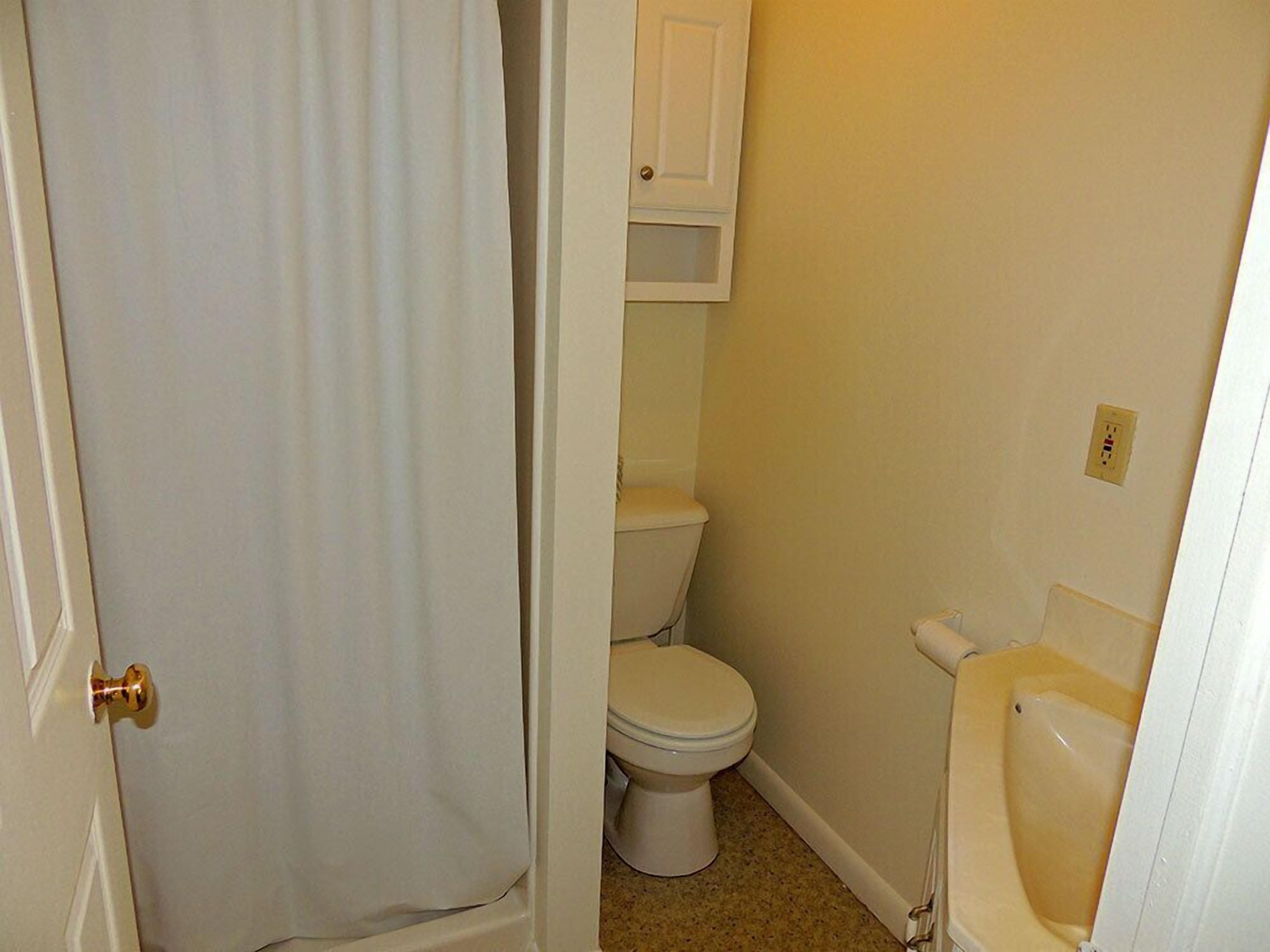 Baño pequeño y funcional con inodoro, lavabo y cortina de ducha.