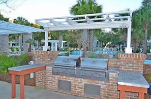 An outdoor barbecue area with a brick grill and a pergola structure.