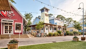 A building with a Cream & Desserts sign, a tower, and string lights. - Baytowne Wharf - 4th Floor Corner Apartment (Sandestin)