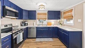 Une cuisine moderne avec des armoires bleues, des appareils en acier inoxydable et un plancher en bois.