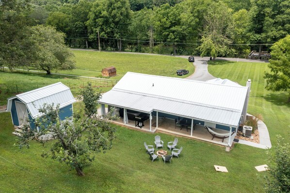 A large house with a covered patio, a small shed, and a lawn.