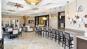 Una cocina moderna con una isla central, asientos tipo bar y un área de comedor con mesas y sillas.