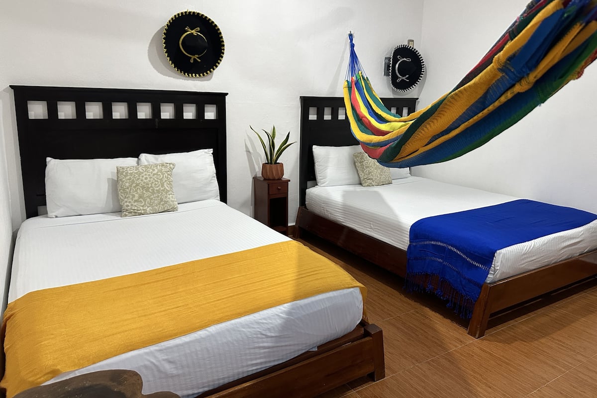 Una habitación de hotel con dos camas, una hamaca y una planta en maceta.