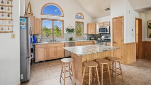 A spacious kitchen with wooden cabinets, a large island with stools, a refrigerator, a microwave, and a stove. - 2 min to beach, Private Pool & Hot Tub. Ocean Hill (Corolla)