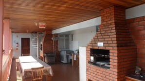 A covered outdoor dining area with a brick oven, a staircase, and a sign indicating the exit. - Apart Hotel La Cabana (Florianópolis)
