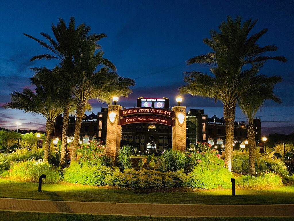 The Florida State University DeVoe L. Moore University Center at dusk with illuminated entrance and palm trees.