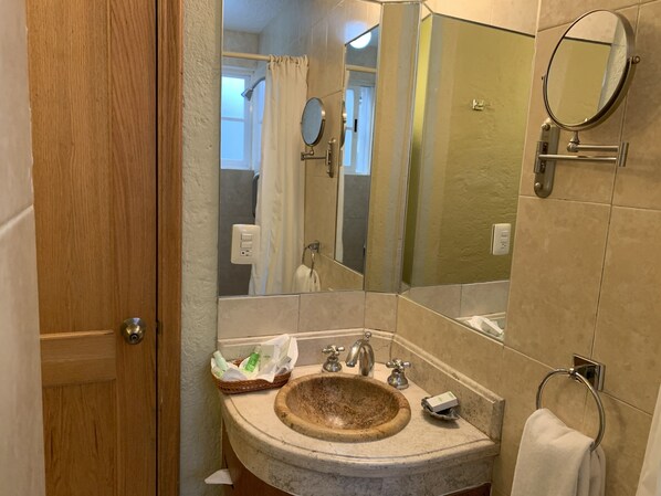 Une salle de bain avec une porte en bois, un lavabo avec un receveur, un miroir et un porte-serviettes.