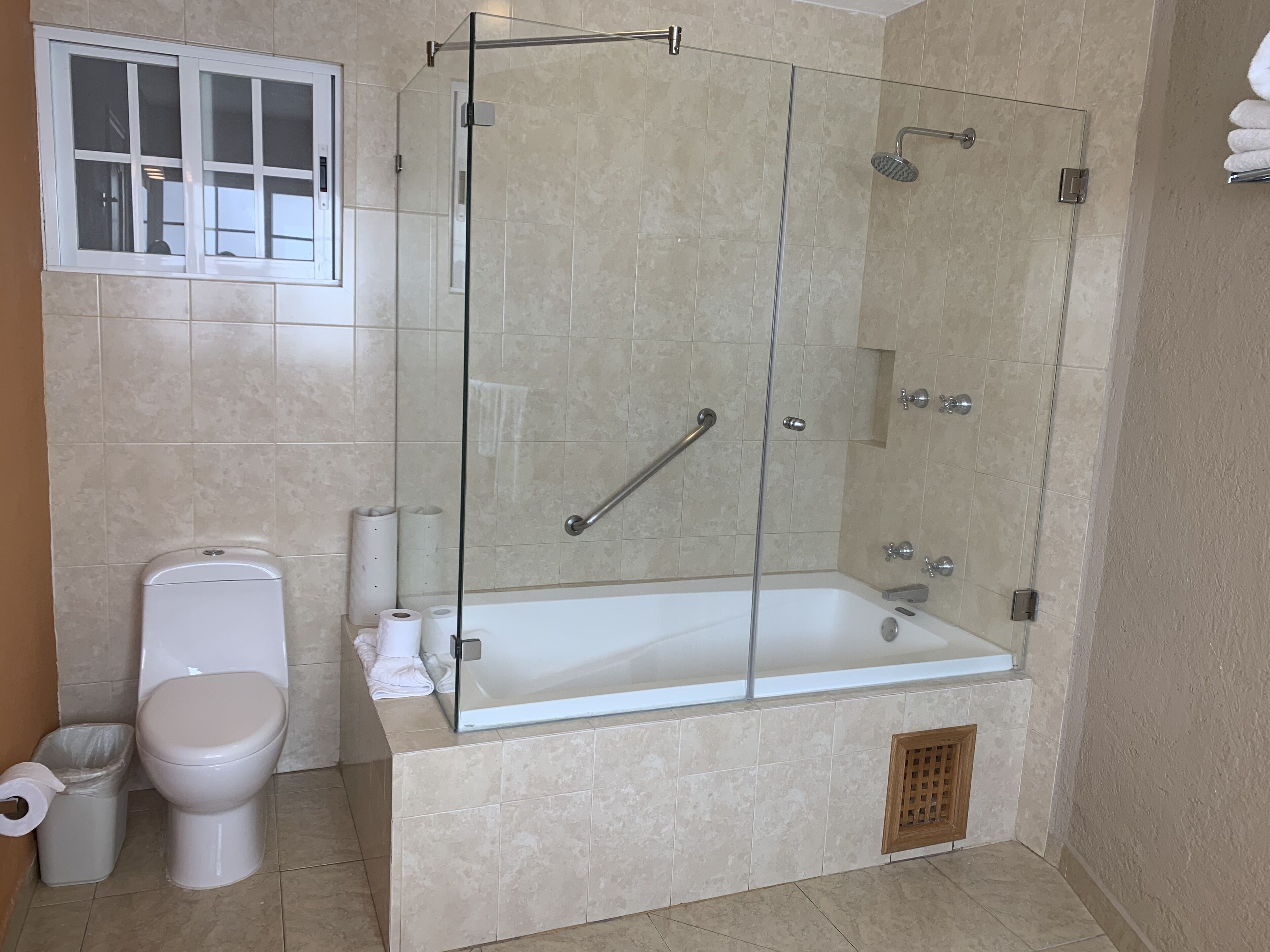 A modern bathroom with a glass-enclosed shower, a toilet, and a bathtub.