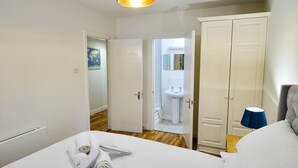 Une chambre d’hôtel avec un lit, une armoire, une salle de bain visible à travers une porte ouverte et un luminaire au plafond.