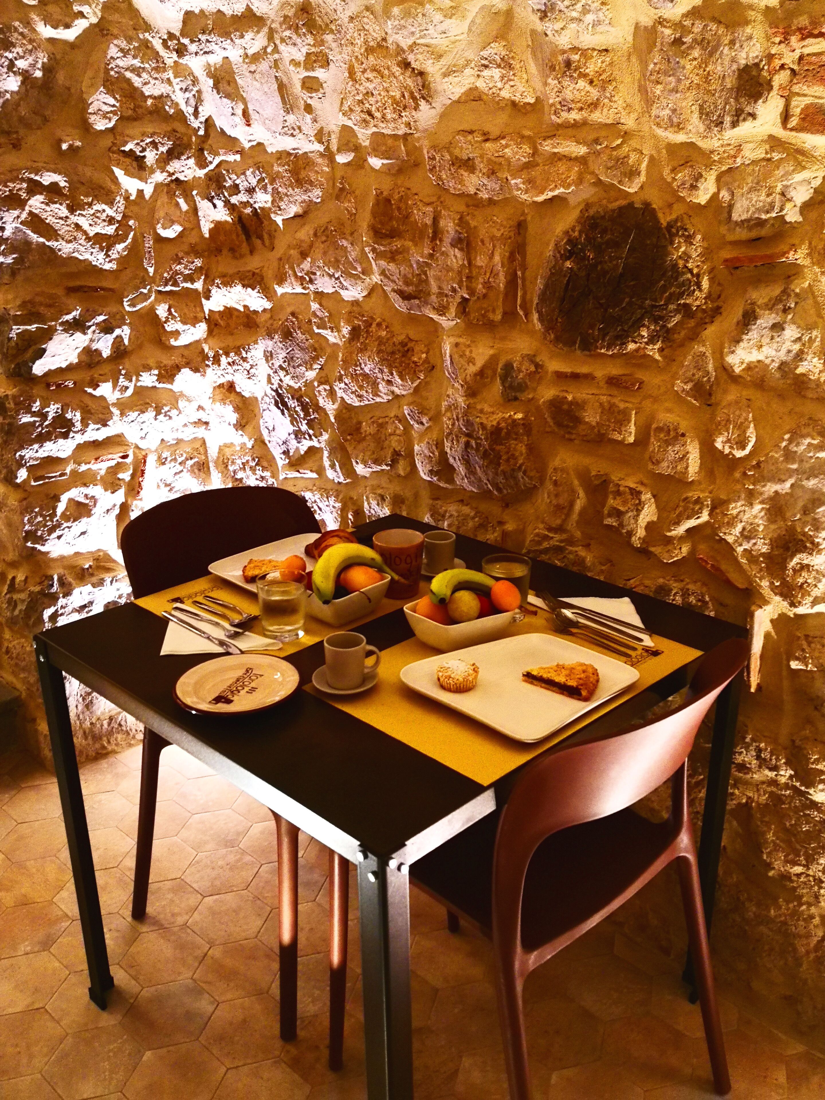 A table set for breakfast with plates, bowls, and a cup, against a stone wall.