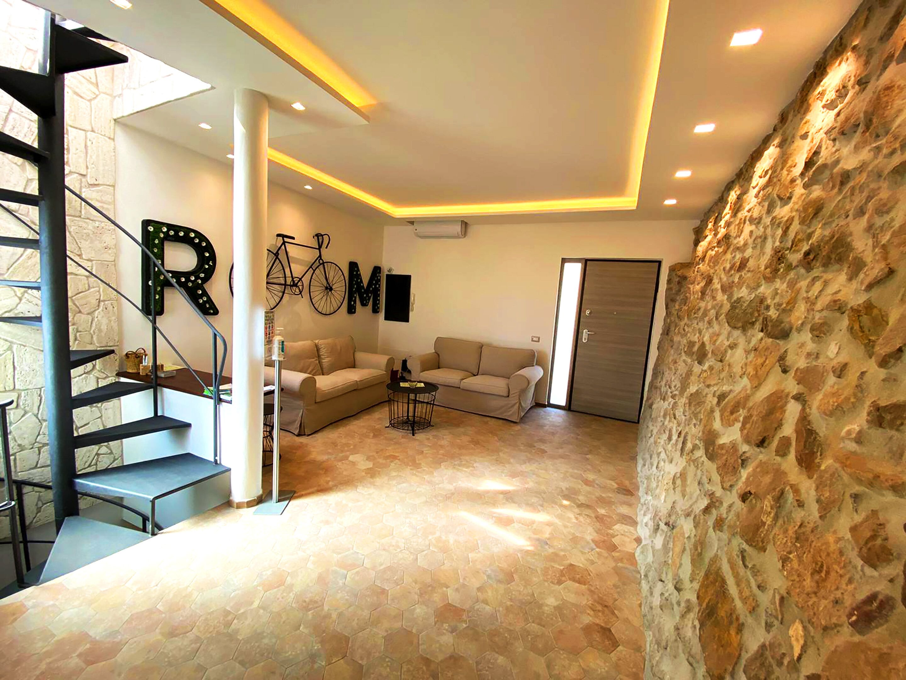 Uma sala de estar ampla com parede de pedra, escada e um conjunto de sofás.