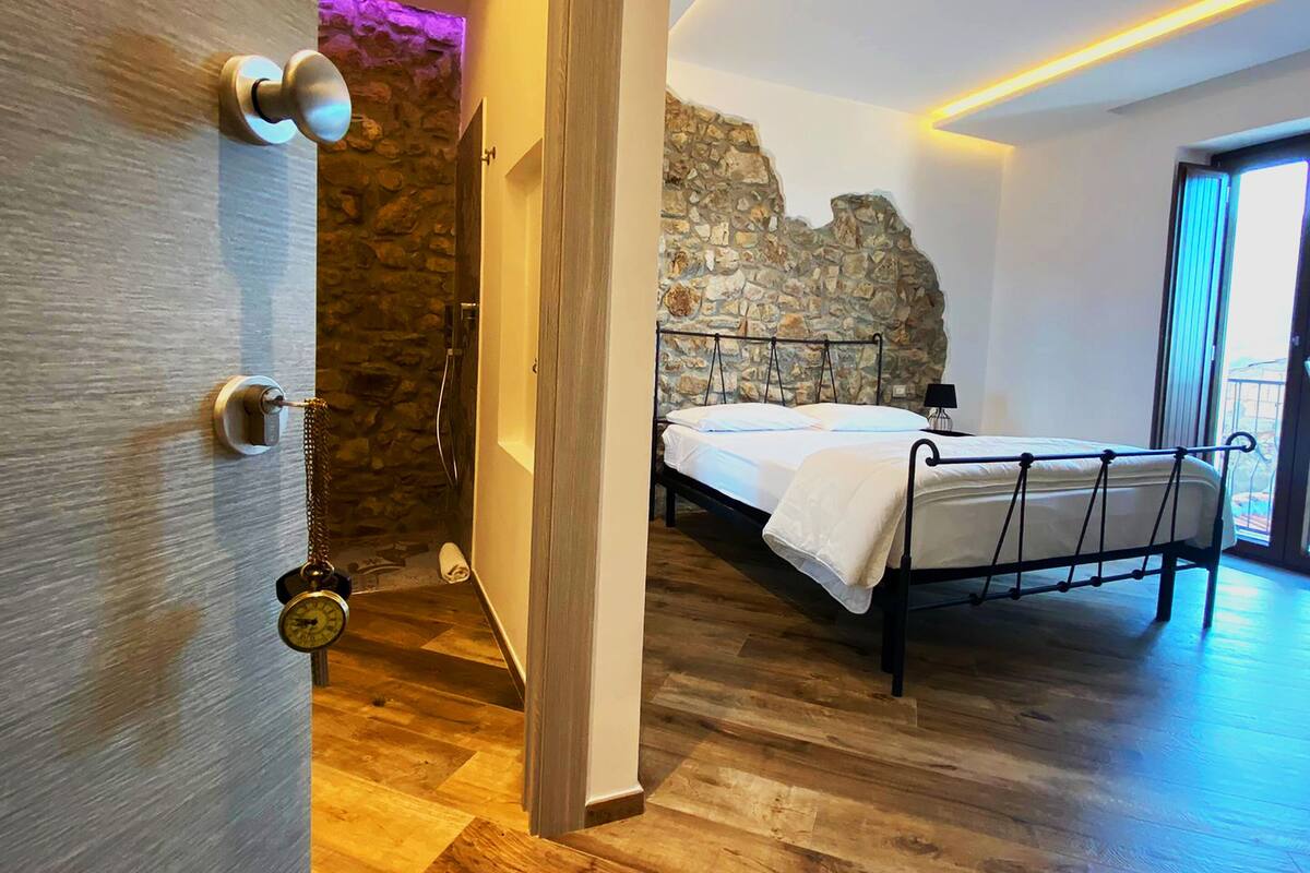 A bedroom with a stone wall, a bed, and a wooden floor.