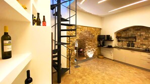 Una cocina moderna con pared de piedra, una escalera de caracol y botellas de vino en estantes.