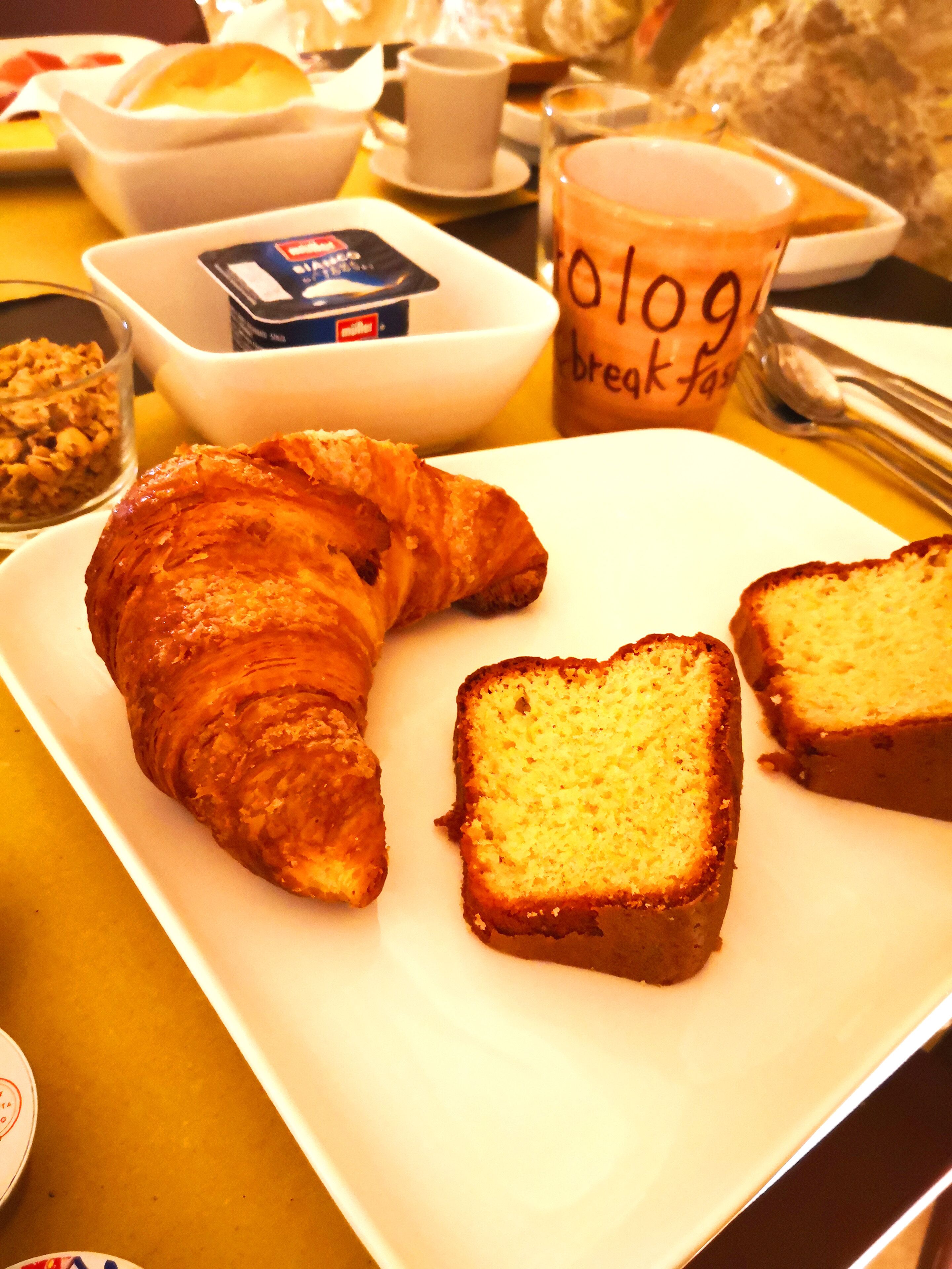 Un plato de desayuno con un croissant y rebanadas de pan sobre un plato blanco.