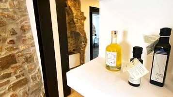 Quarto com parede de pedra e prateleira branca exibindo garrafas de vinho.