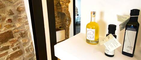 A room with a stone wall and a white shelf displaying bottles of wine.