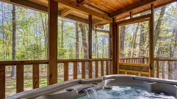 Ein Whirlpool mit Holzterrasse und großen Fenstern mit Blick auf einen Wald.