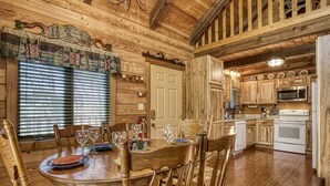 Ein Holzinterieur mit einem Esstisch für vier Personen, Holzschränken, einer Mikrowelle und einem Kühlschrank.