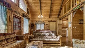 L’intérieur d’une cabane en rondins, avec un canapé, une table basse et un coin repas.