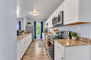 A modern kitchen with white cabinetry, a stainless steel oven, and a microwave. - Shortstop Apt 2 - All Star Baseball Rentals (Oneonta)
