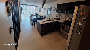 Una cocina moderna con una isla central, muebles oscuros y electrodomésticos de acero inoxidable.
