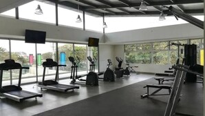 Un gimnasio con cintas de correr, elípticas y equipo de levantamiento de pesas.