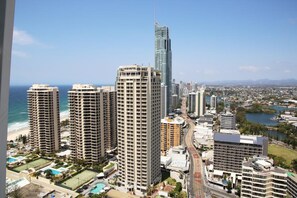 A high-rise hotel with multiple floors, a modern glass facade, and a view of the beach and ocean.
