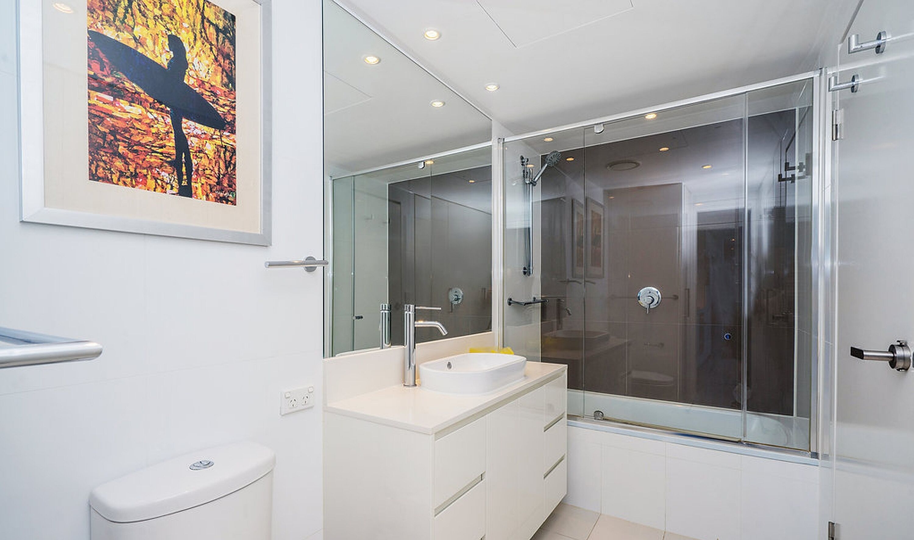 Ein modernes Badezimmer mit großem Spiegel, Duschkabine und Toilette.