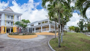 Un hôtel à plusieurs étages doté d’une cour intérieure, d’un espace extérieur aménagé pour s’asseoir et de palmiers.