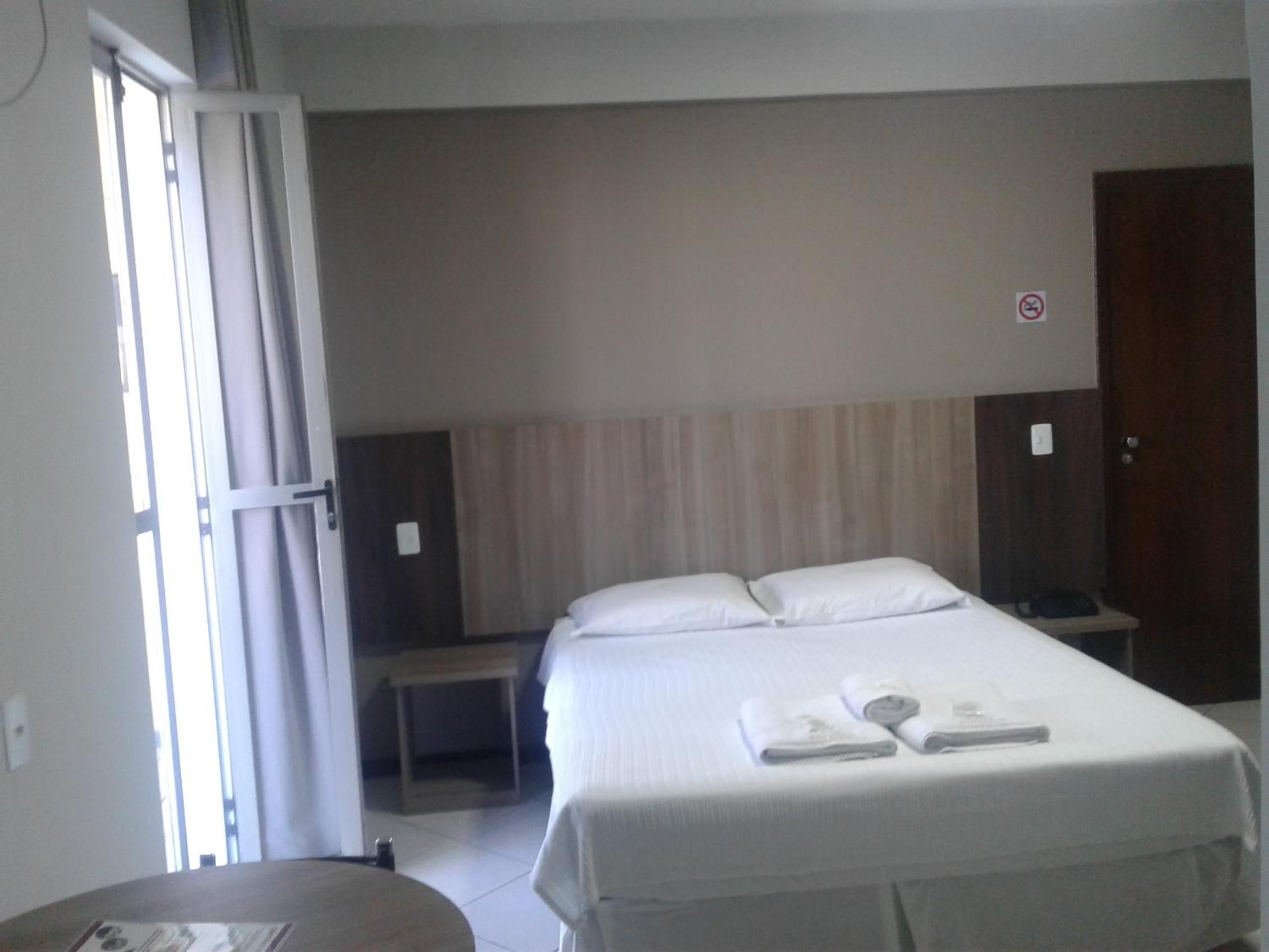 Ein Hotelzimmer mit Bett, Nachttisch, Sessel und Tür.